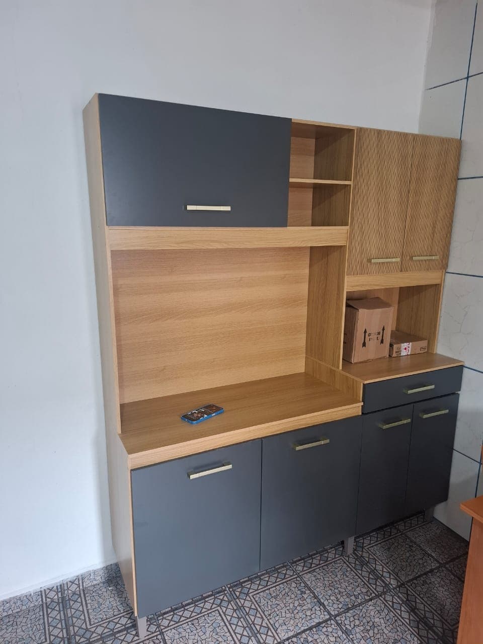 Armário de cozinha em grafite e madeira clara, com nicho central para micro-ondas e balcão inferior