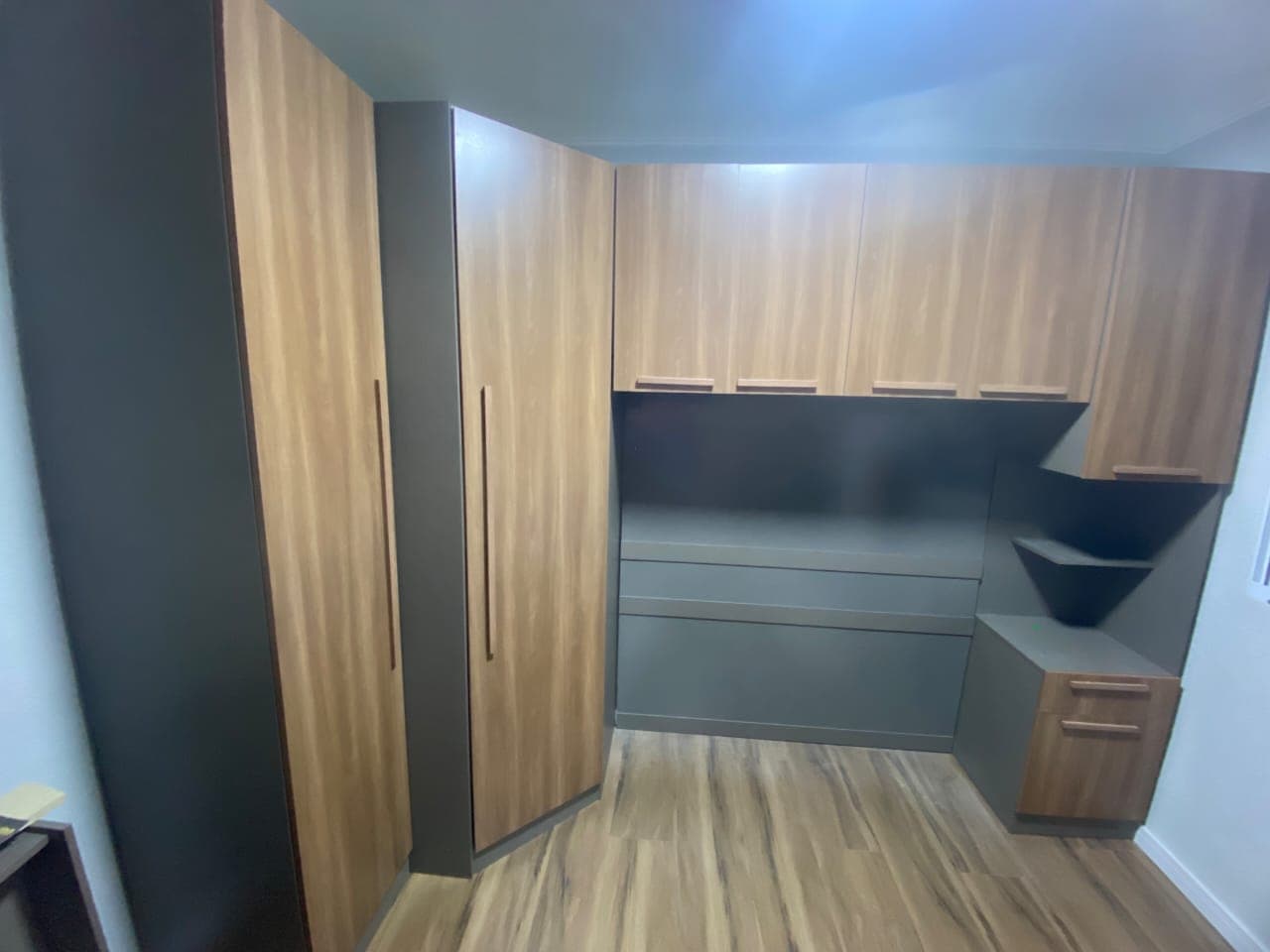 Closet planejado em amadeirado e grafite, com portas altas, gaveteiro e prateleiras de canto